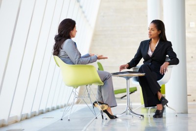 Two business women sitting at a table having a meeting.