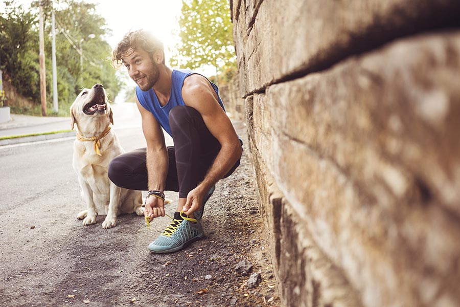 Man tying shoe with his dog