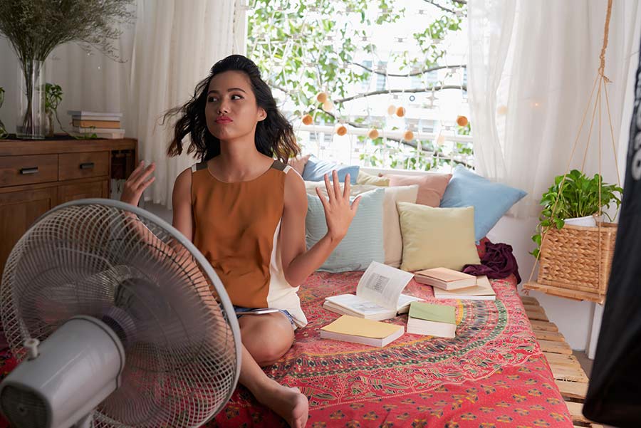 Girl sitting in front of a fan on a hot day
