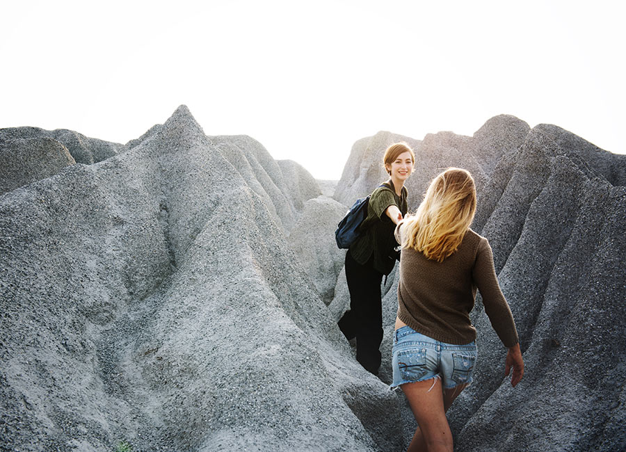 Two women helping each other hiking