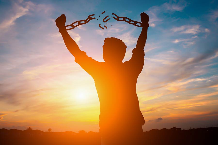 Young man breaking the chains on his wrists