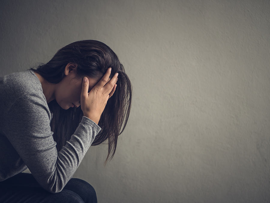 Brunette woman with her head in hands. She appears distressed.
