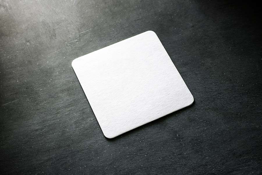 A white drink coaster sitting on a black table