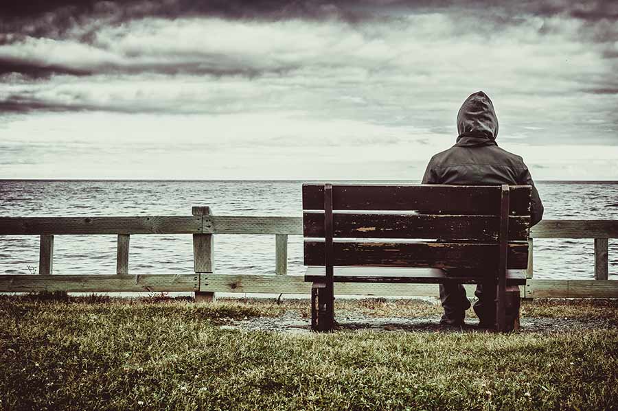 man on bench looking at ocean