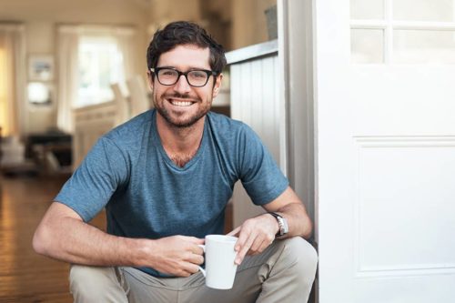 man smiling and holding a mug