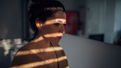 woman standing in the dark by a window