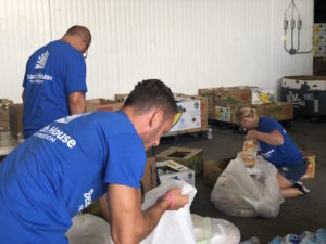 Beach House volunteers wearing blue T shirts and packing produce.