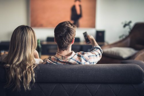 Couple relaxing on couch, enjoying TV time together