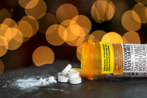 An overturned bottle of oxycodone opioid tablets with the tablets spilling out.