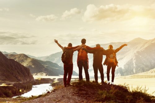 Group of four atop a mountain, arms raised in triumph