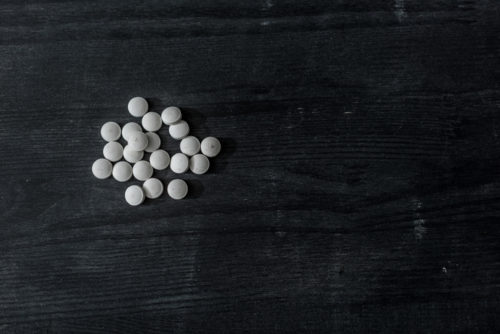 White pills scattered on a black table surface
