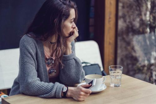 A woman sitting with her coffee and phone