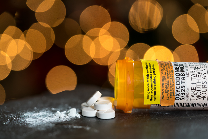 An overturned bottle of oxycodone opioid tablets with the tablets spilling out.