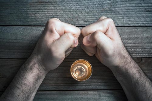 Hands holding a gold coin atop a wooden surface