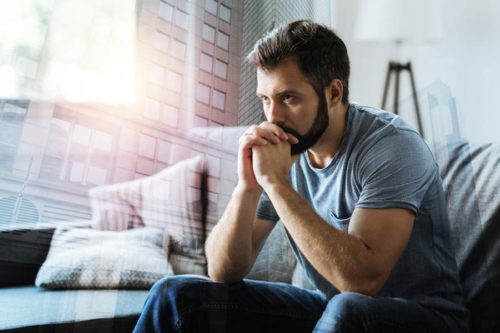 Man in contemplation, seated on couch