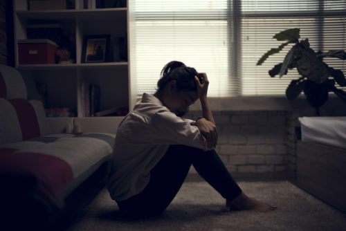Woman sitting on floor near window
