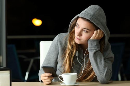 Woman in hoodie listening to music on her phone