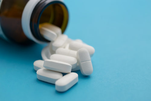 Pills scattered from a bottle on a blue background