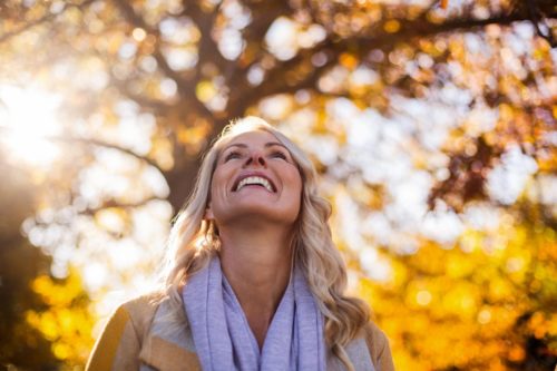 Woman smiling in sunlight, looking up joyfully