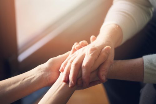 A woman supporting another by holding hands