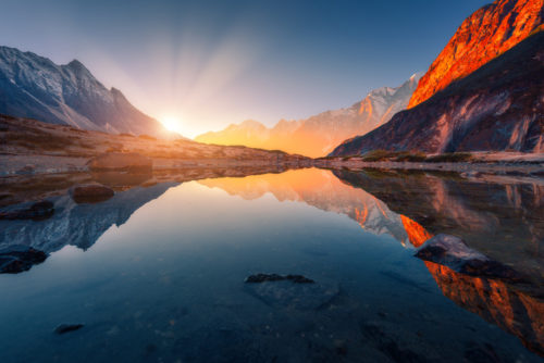 Sunrise over mountains reflected in serene lake