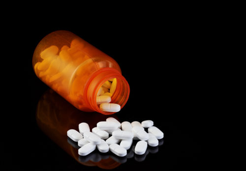Pills spilled from bottle on dark background