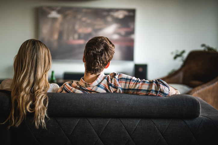 Two people relaxing on couch, watching TV