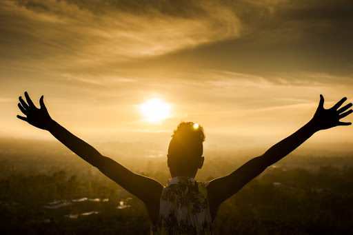 Woman embracing sunlight with outstretched arms