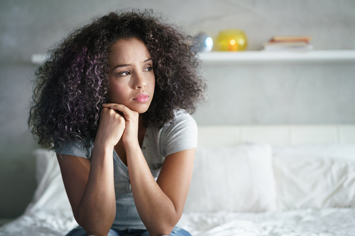 Woman thoughtfully resting on bed