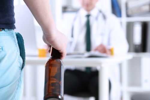 Man with alcohol bottle before doctor