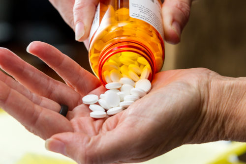 Hand holding medication and pill container