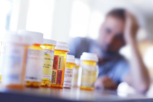 Man at table with prescription bottles
