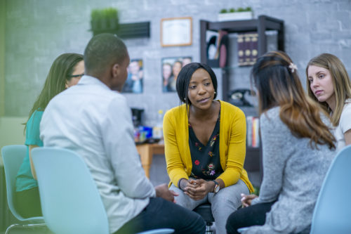 A group of men and women taking part in a group therapy session.