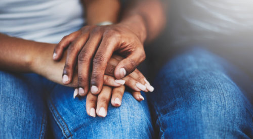 a close up of a couple holding hands while sitting next to each other