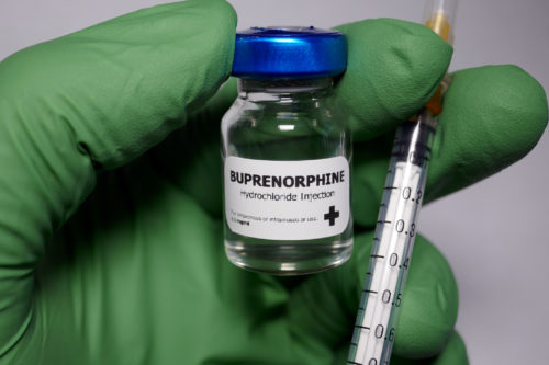 A a vial of Buprenorphine with a syringe and needle in front of it.