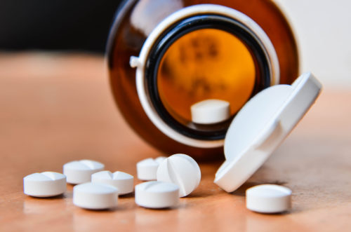 Bottle of pills beside a white pill on a table