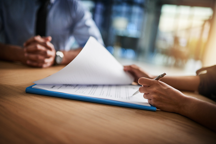 Two people looking over and signing a contract.