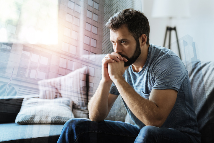 A man sitting on a couch looking pensive.