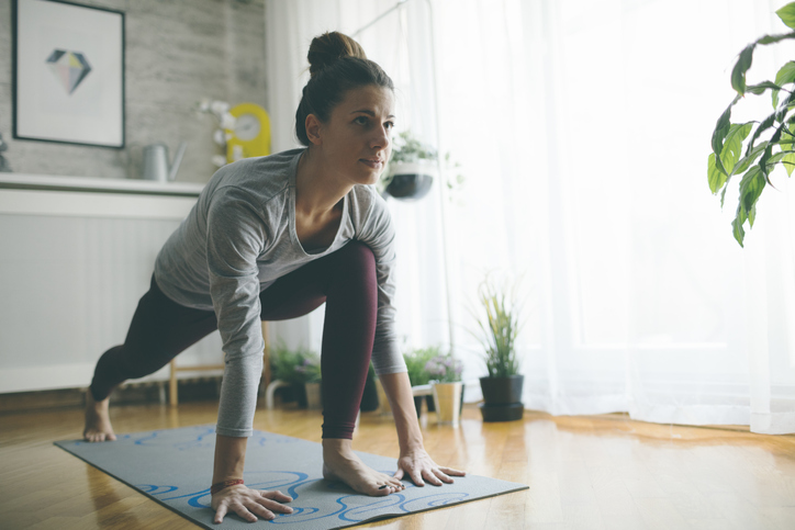 A young woman practicing iyengar yoga at home in her living room.