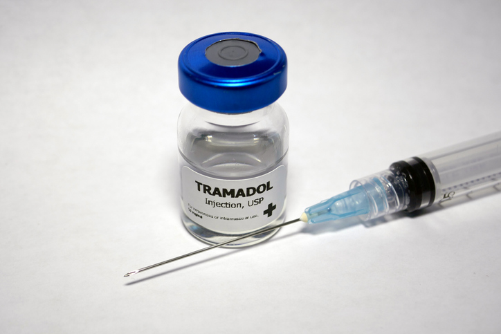 A a vial of tramadol with a syringe and needle in front of it.
