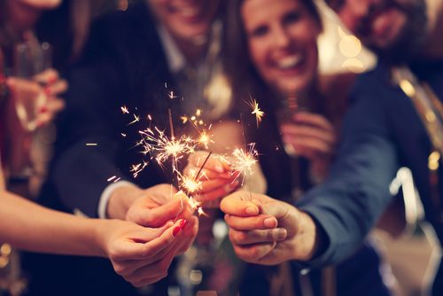 A group of male and female friends smiling and having fun with sparklers.