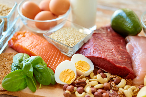 A variety of natural rich in protein food on table, including various meats, eggs and nuts.