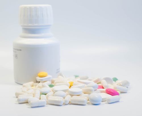 Pill bottle next to scattered pills on a clean surface