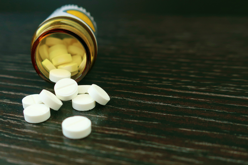 A bottle of pills tipped over, scattering on the table