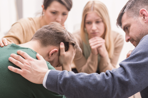 A group of men and women holding an intervention for a young man.