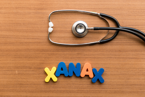 Xanax spelled out in colorful letters with stethoscope on wooden background.