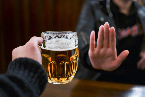 A women rejecting the offering of a pint of beer.