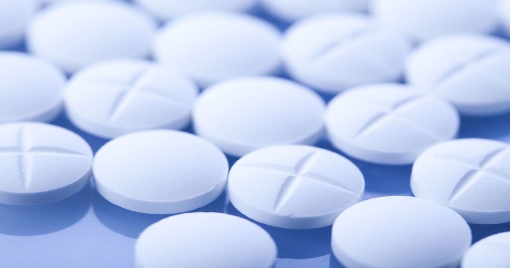 A close up of white Benzodiazepine tablets laid out on a blue tabletop.