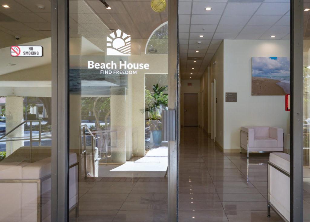 The front door and hallway leading into Beach House reception with a view of the logo on the door.