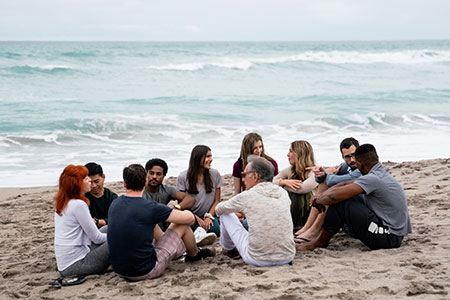 A group of men and women smiling during a therapy session on the Beach.